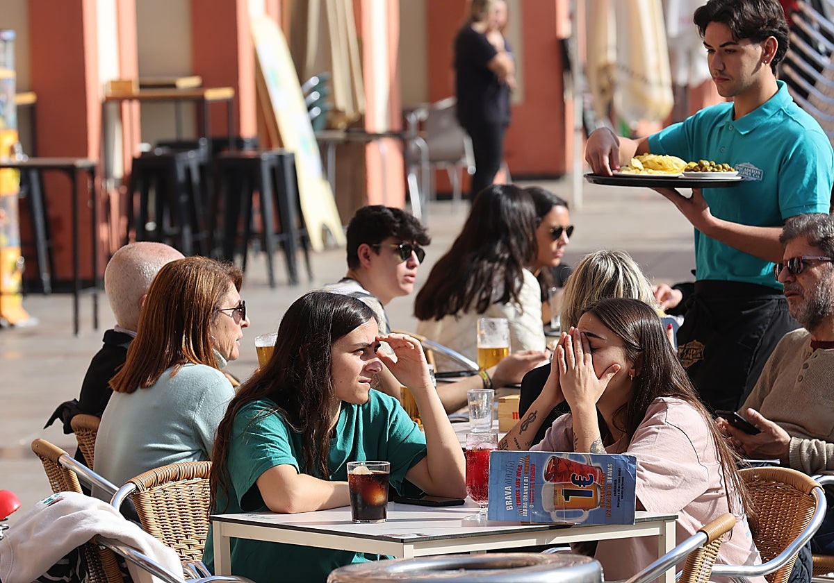 Un joven camarero atiende mesas en una terraza de la plaza de la Corredera