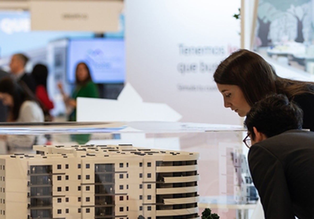 Dos jóvenes miran la maqueta de una promoción de viviendas