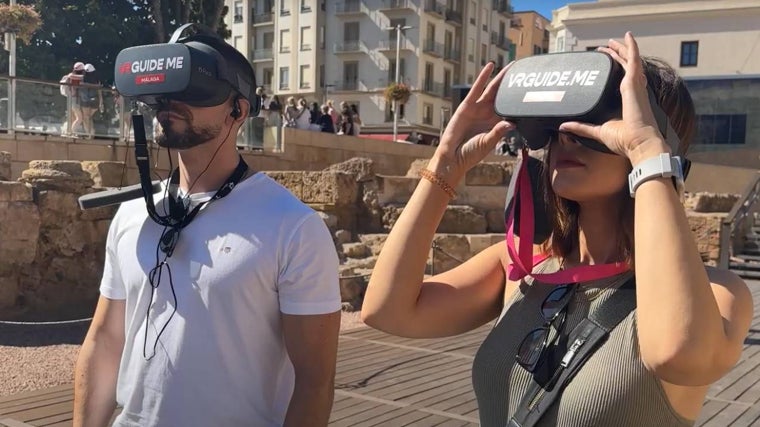 Dos turistas utilizan las gafas de realidad virtual en el Teatro Romano de Málaga