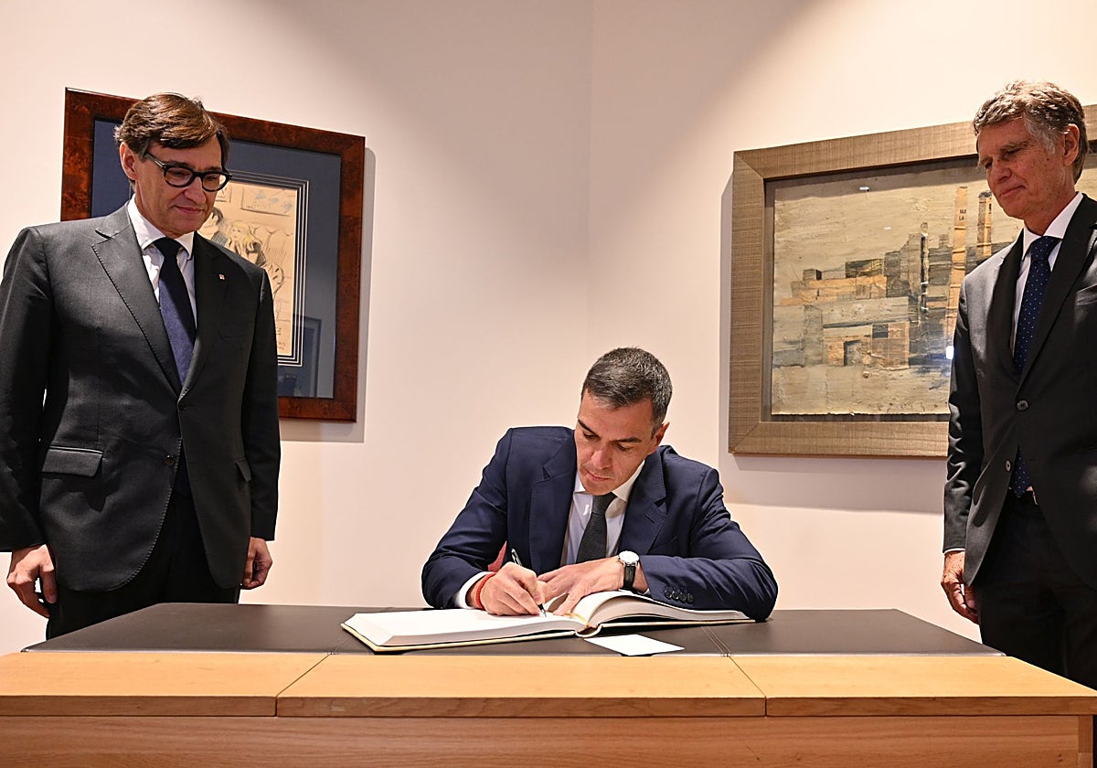 Sánchez firma en el libro de honor, flanqueado por Salvador Illa y Jaume Guardiola