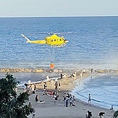La extinción de un incendio en el Castillo de Santa Bárbara de Alicante con un helicóptero cargando agua en la playa