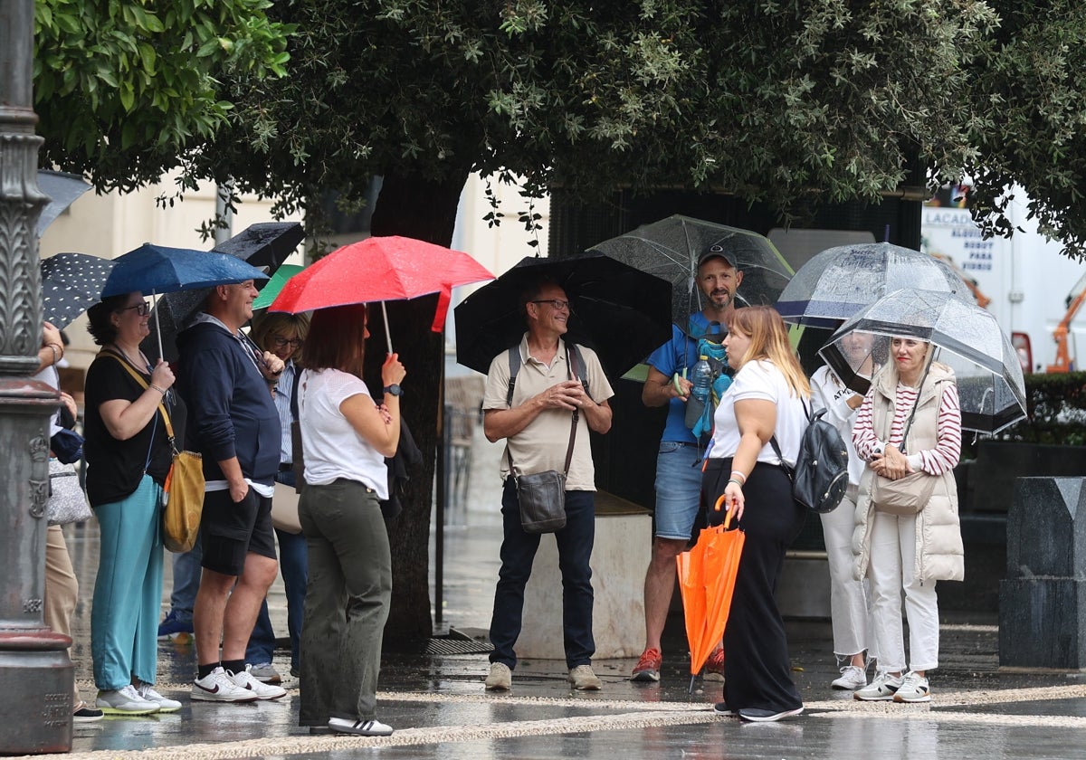 Un grupo de turistas bajo el paraguas esta tarde en la plaza de las Tendillas