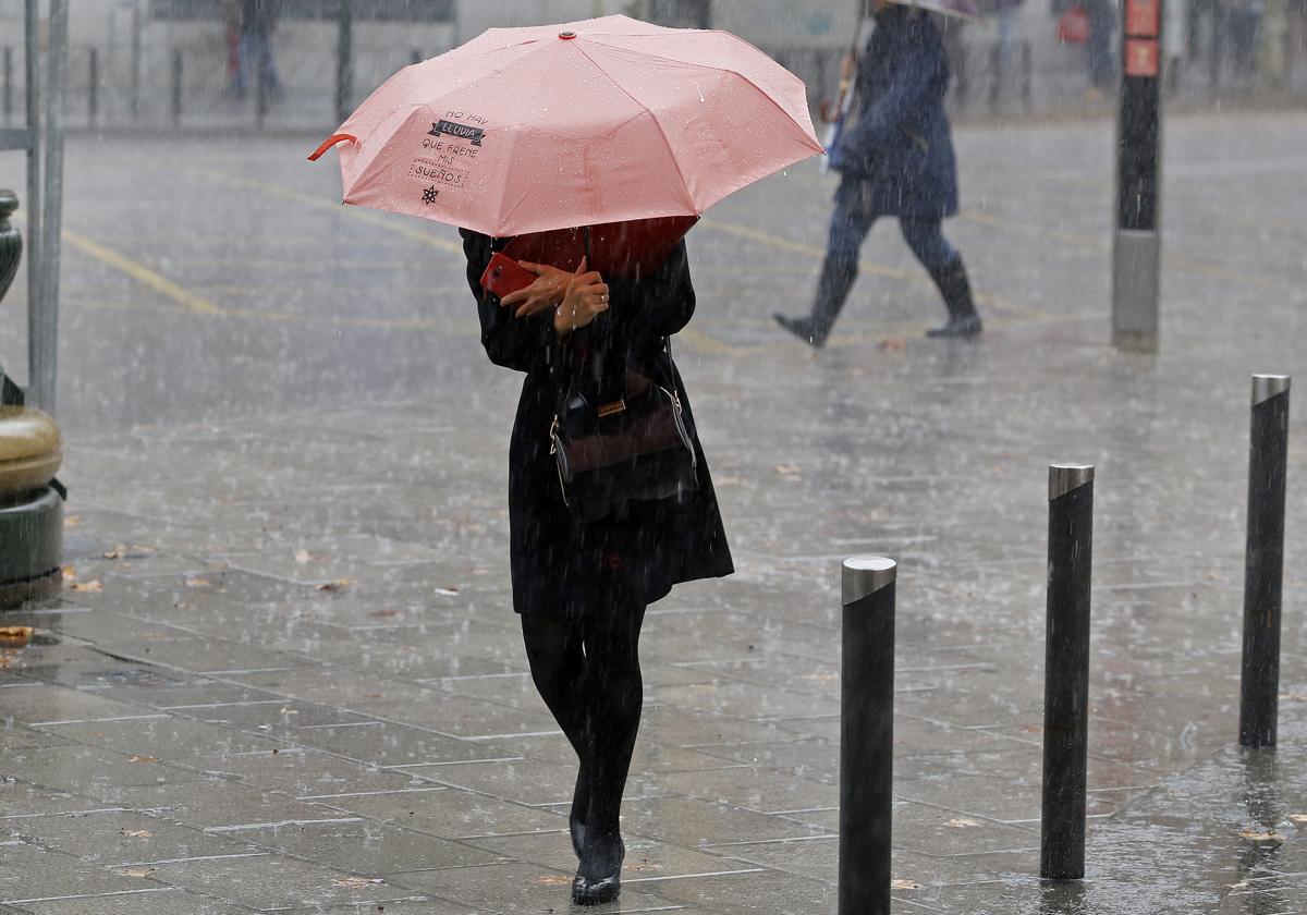 Una mujer se protege de la lluvia durante un día de temporal