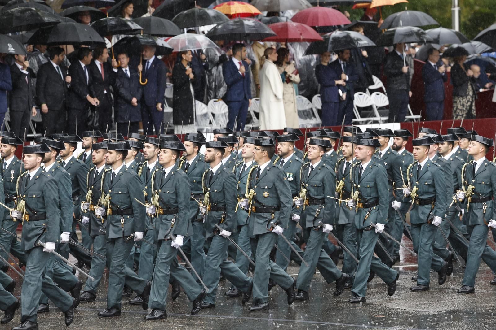 Decenas de efectivos de la Guardia Civil pasean frente a las autoridades bajo una intensa cortina de agua