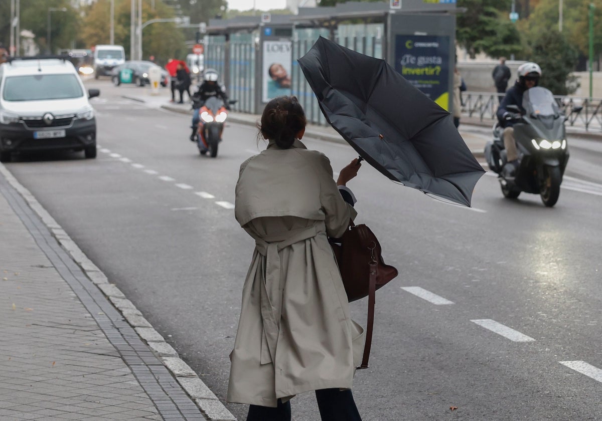 Una mujer se refugia de la lluvia en Madrid