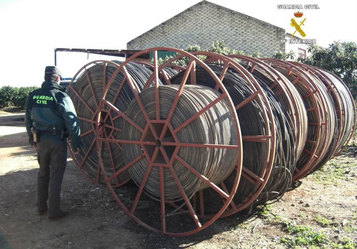 Un agente de la Guardia Civil junto a metros de cable de cobre robados en una operación