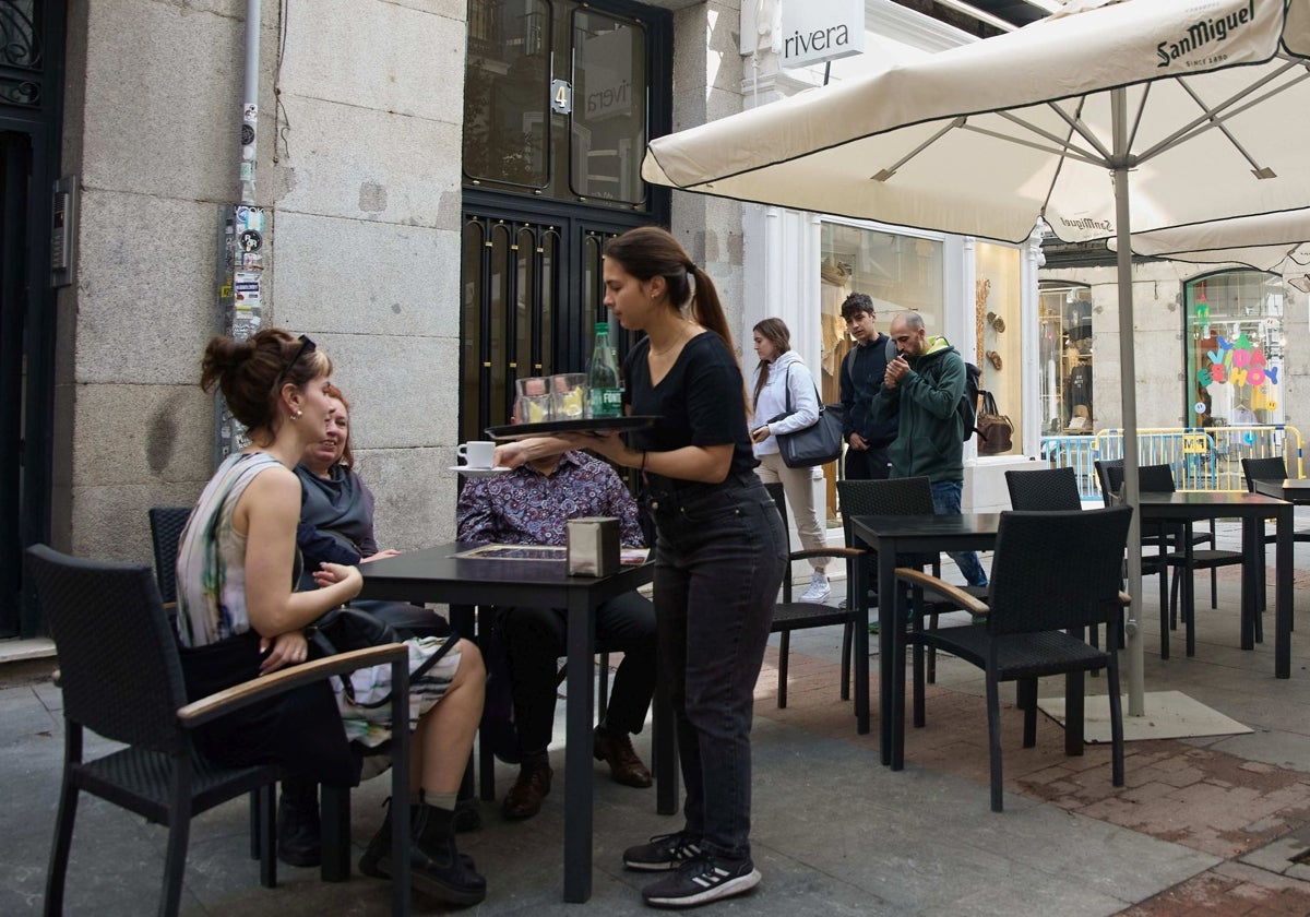 Una camarera sirve en una terraza en una fotografía de archivo.