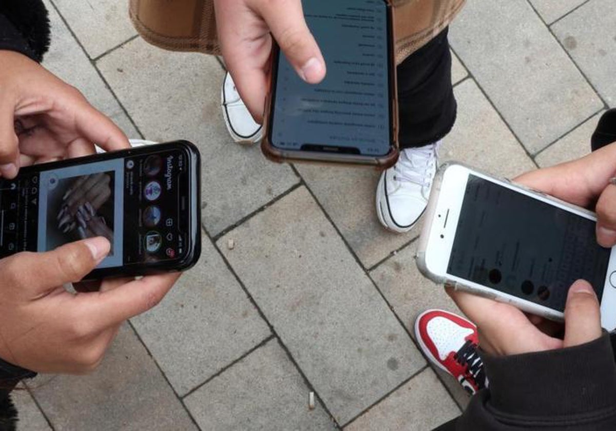 Imagen de archivo de varios jóvenes usando sus teléfonos móviles