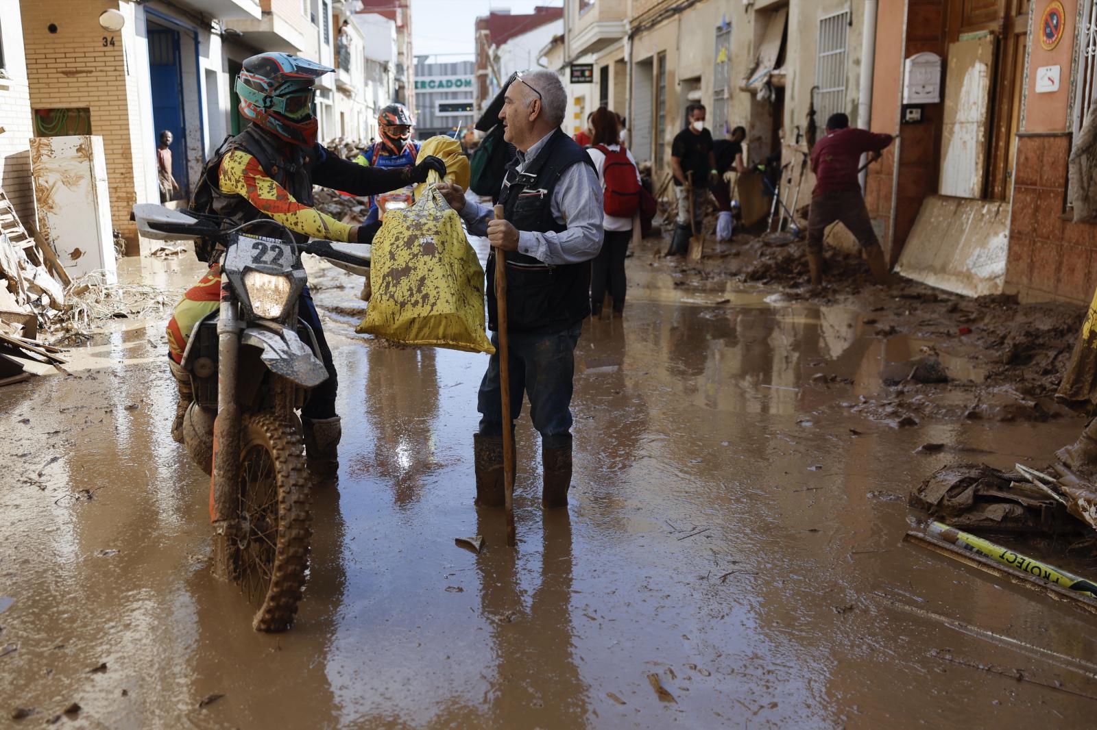 Entrega de utensilios para ayudar en la limpieza en una calle de la localidad de Masanasa, en Valencia