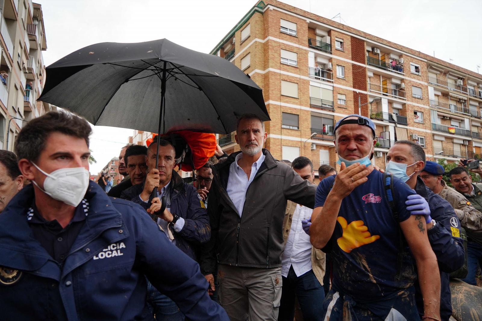 El rey Felipe VI de España está protegido con un paraguas mientras los residentes enojados lo interrumpen y le arrojan barro y objetos durante su visita a Paiporta, en la región de Valencia