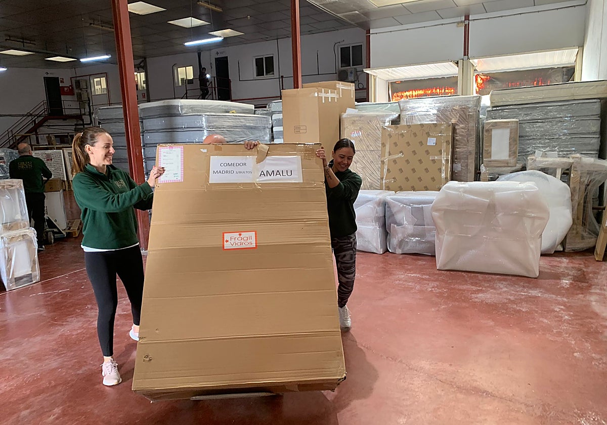 Dos trabajadoras de Grupo SEYS apilan muebles donados para Valencia