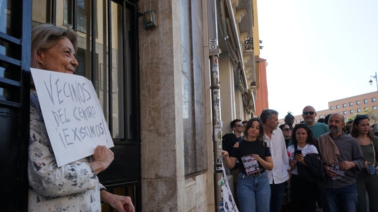 Una vecina de la céntrica calle Carretería de Málaga muestra un cartel durante la manifestación de este sábado en defensa de la vivienda digna