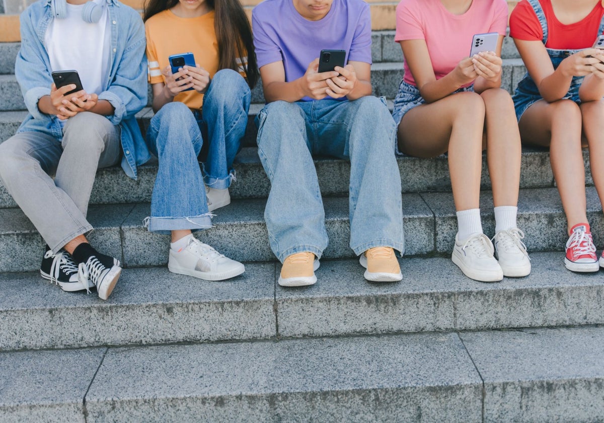 Varios adolescentes utilizando sus teléfonos móviles