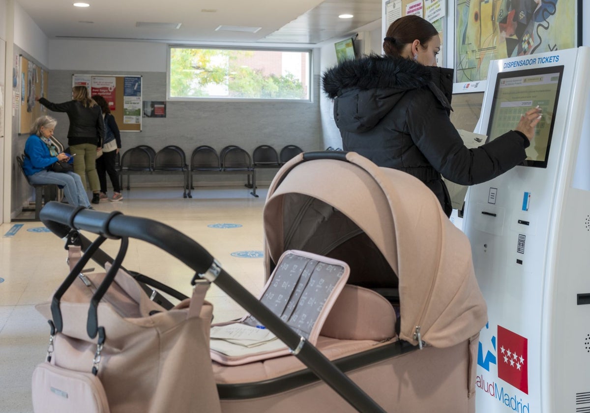 Una usuaria solicitando el ticket de su cita en una de las máquinas dispensadoras en el centro de salud de Valdebernardo