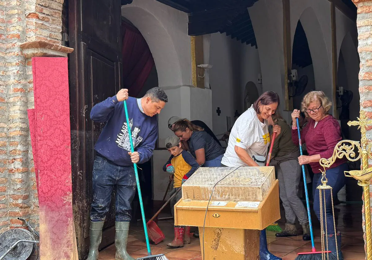 Varios vecinos limpian el interior de la iglesia de Benamargosa tras el paso de la DANA