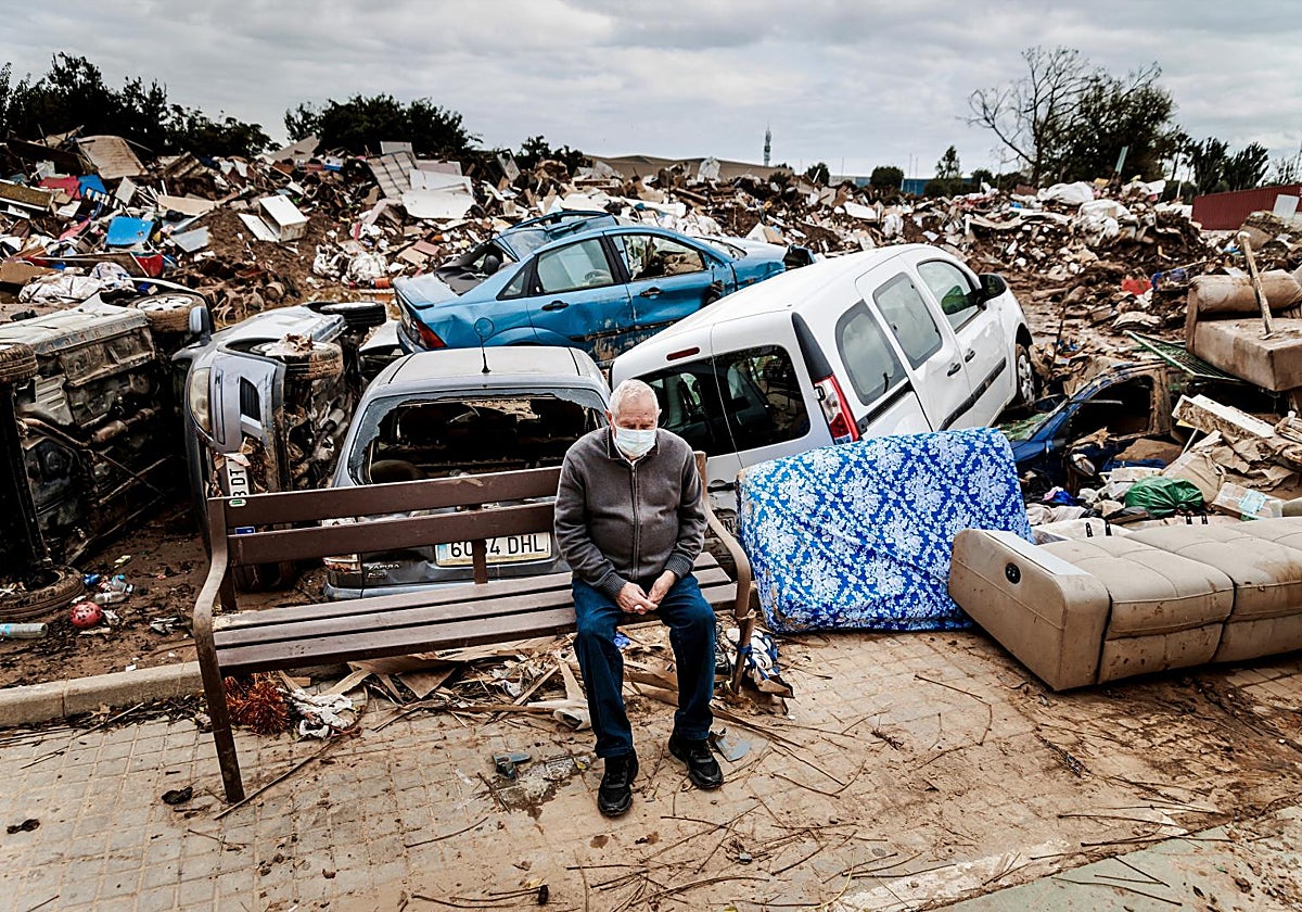 Un hombre observa vehículos y enseres apilados en una zona afectada por las inundaciones causadas por la DANA en Valencia