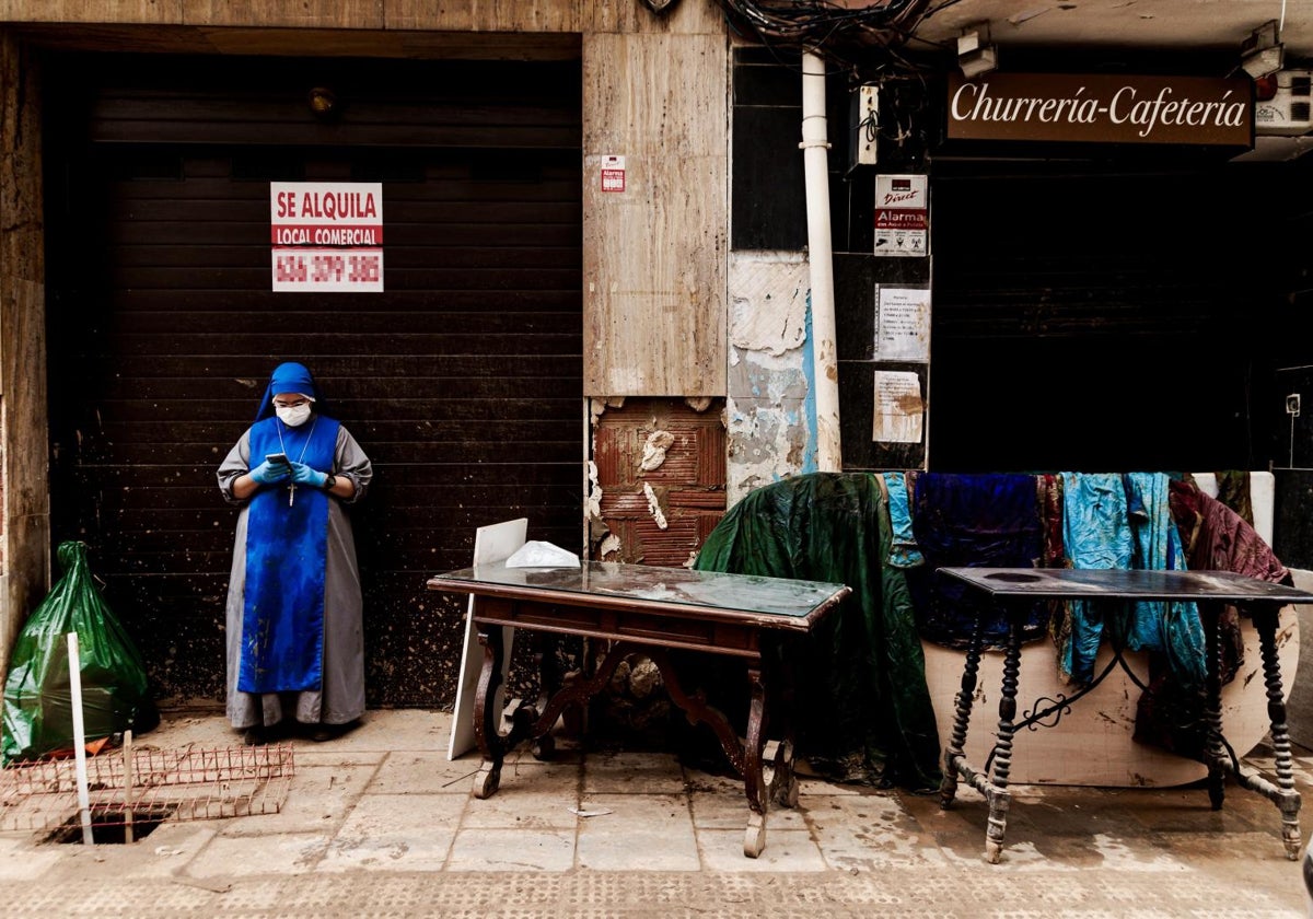 Una monja junto a muebles y ropa en Paiporta, en un espacio afectado por los daños causados por la DANA