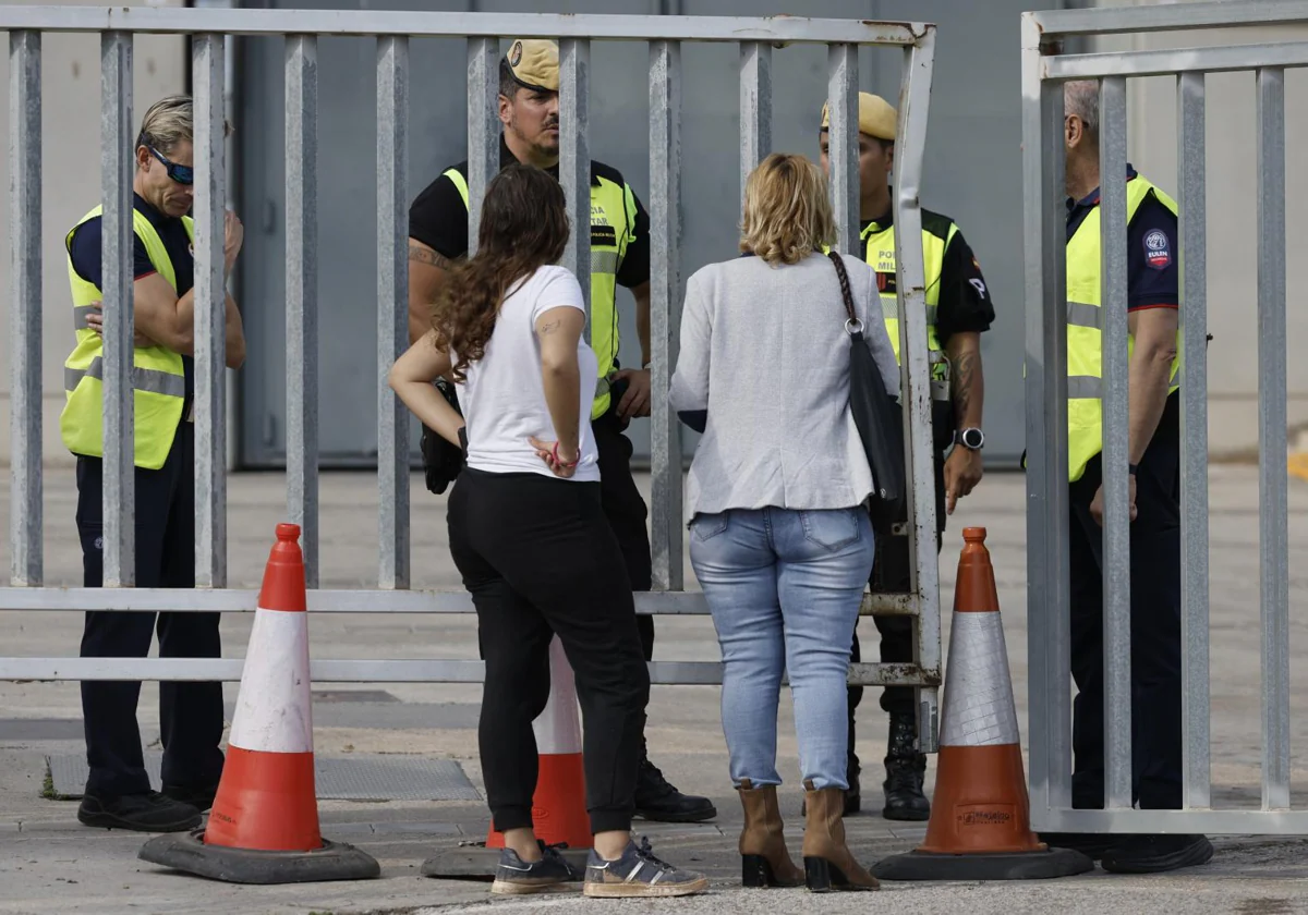 Dos mujeres hablan con militares de la UME en la morgue instalada en Feria Valencia por la catástrofe de la DANA