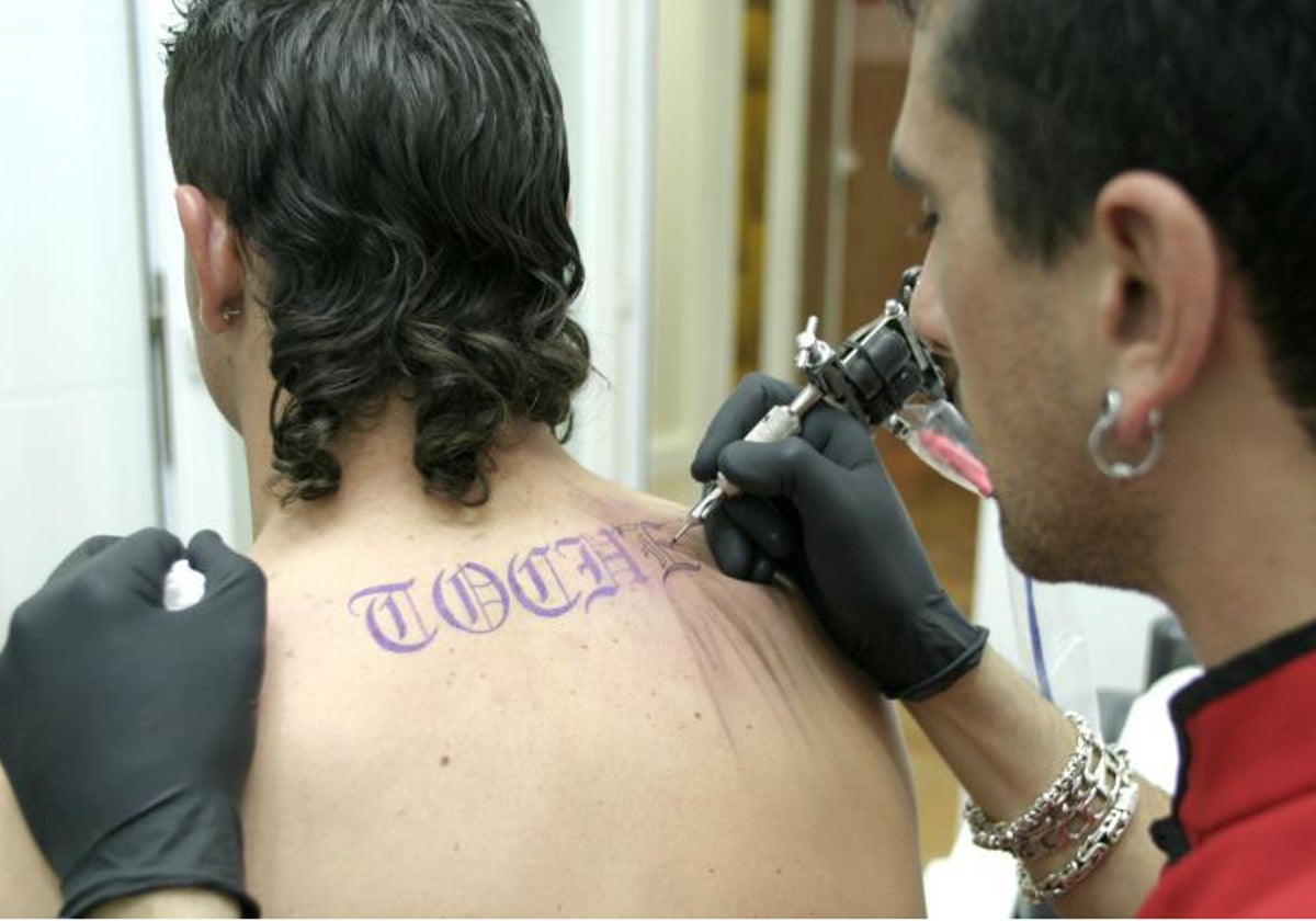 Un joven hace un tatuaje a otro, en imagen de archivo