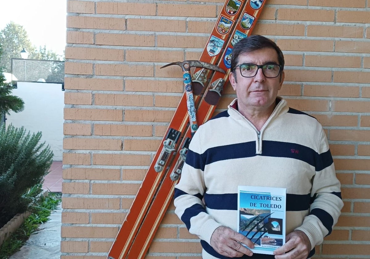 Mariano posa con su libro en la puerta de su casa, delante de unos esquíes y un piolet antiguos