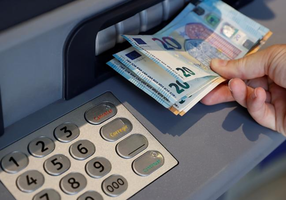 Un usuario saca dinero de un cajero en foto de archivo