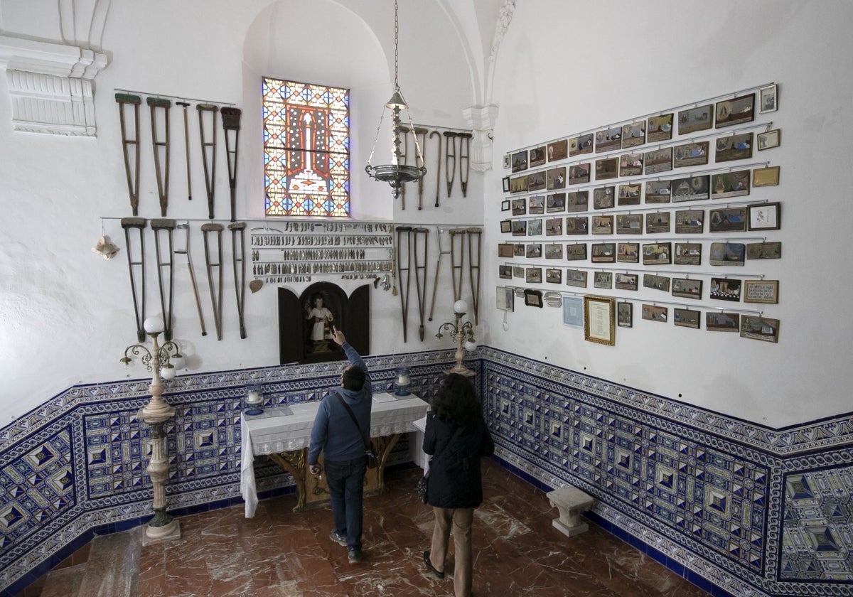 Vista general de la galería de exvotos, en el antecamarín de la Virgen, con muletas, placas y tablillas