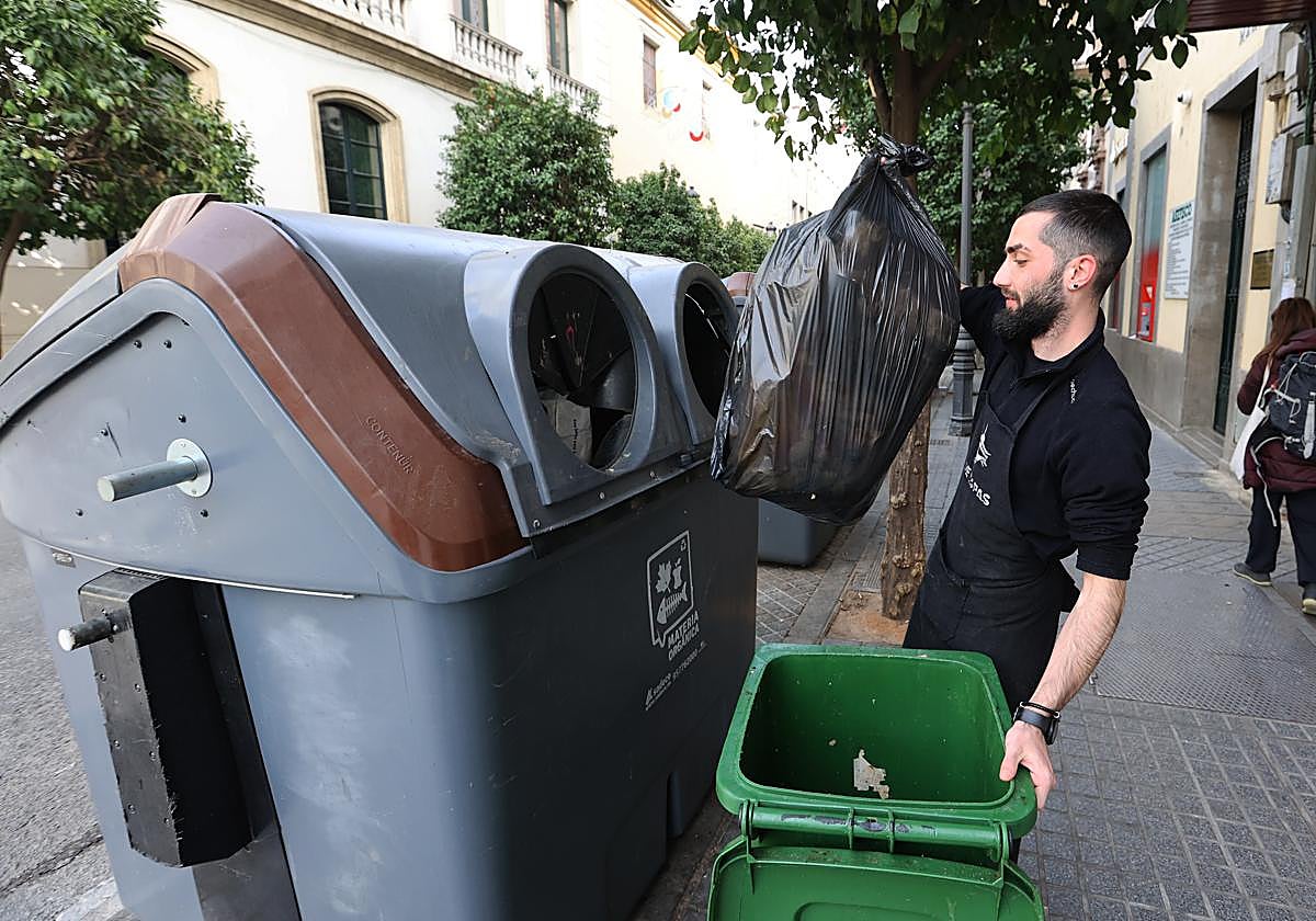 Un trabajador deposita la basura en un contenedor en el Centro de Córdoba