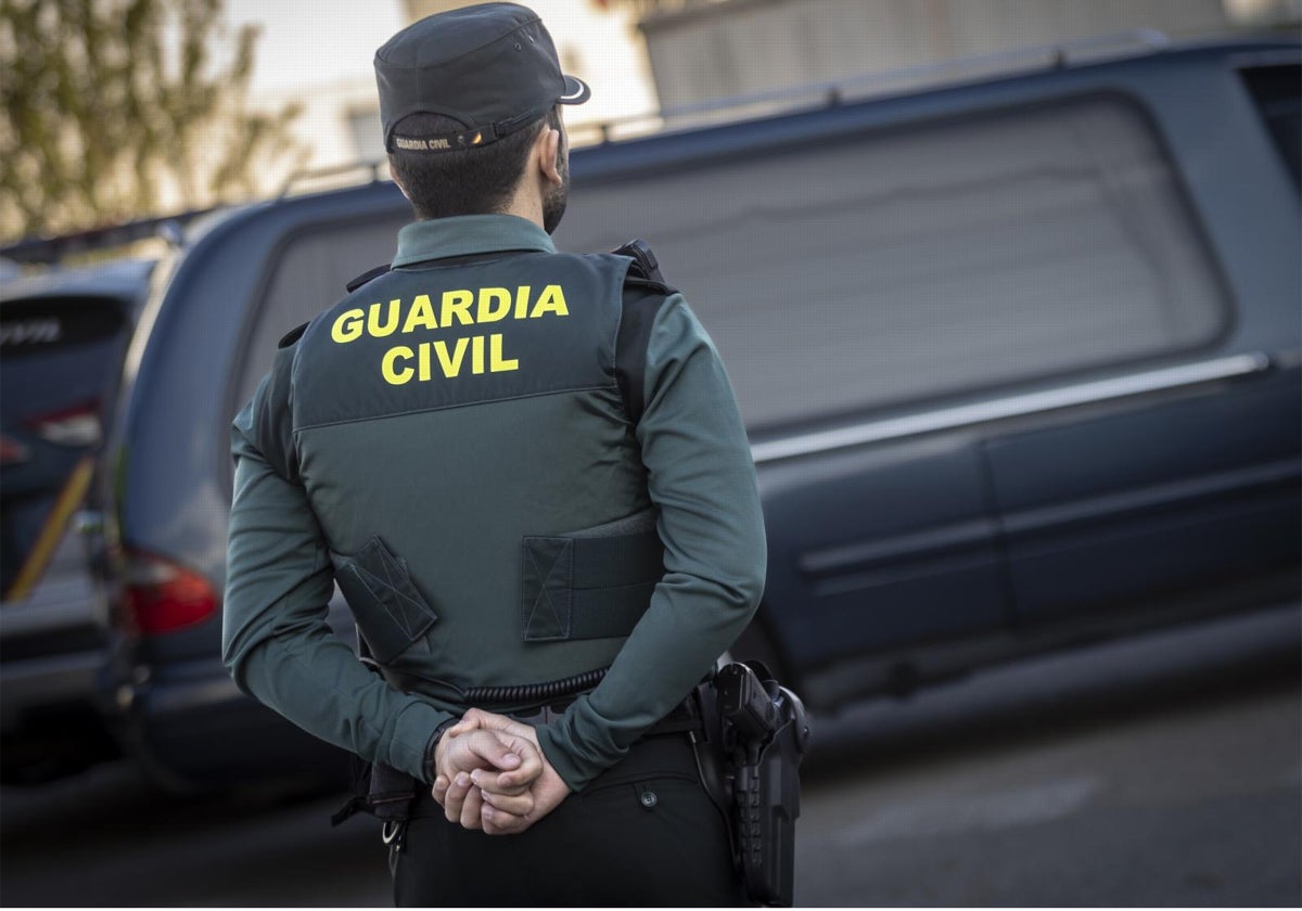 Un guardia civil junto a un coche fúnebre