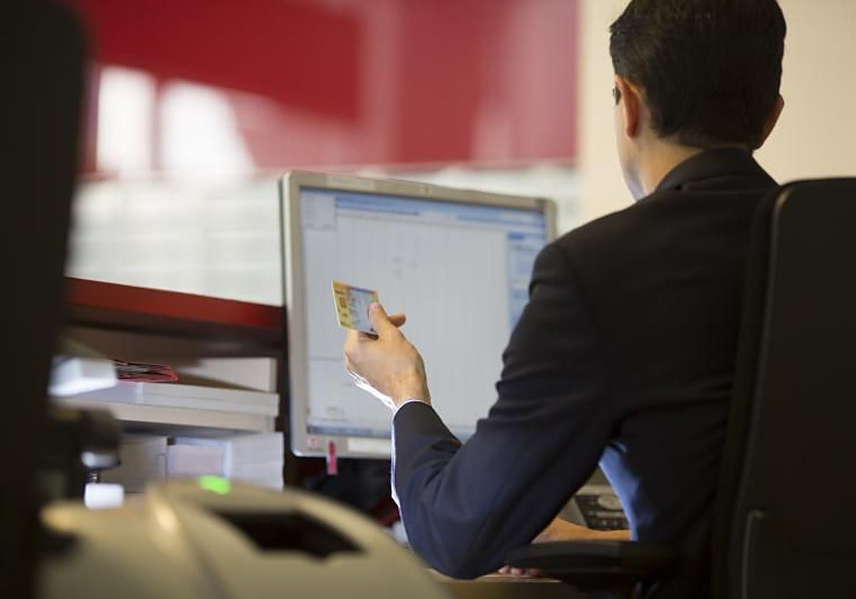 Un agente de banca comprueba el DNI en una entidad financiera