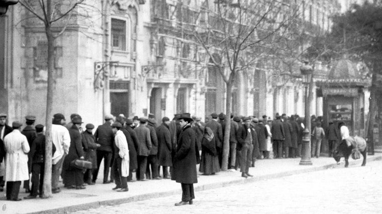 Cientos de hombres hacen cola ante un estanco madrileño para conseguir tabaco, en enero de 1920