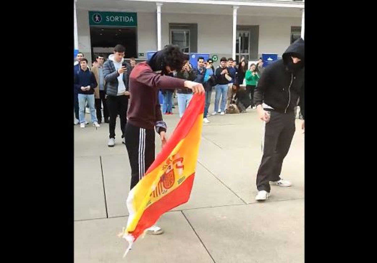 Momento del vídeo subido a X por S'ha Acabat! en el que dos encapuchados queman la bandera de España