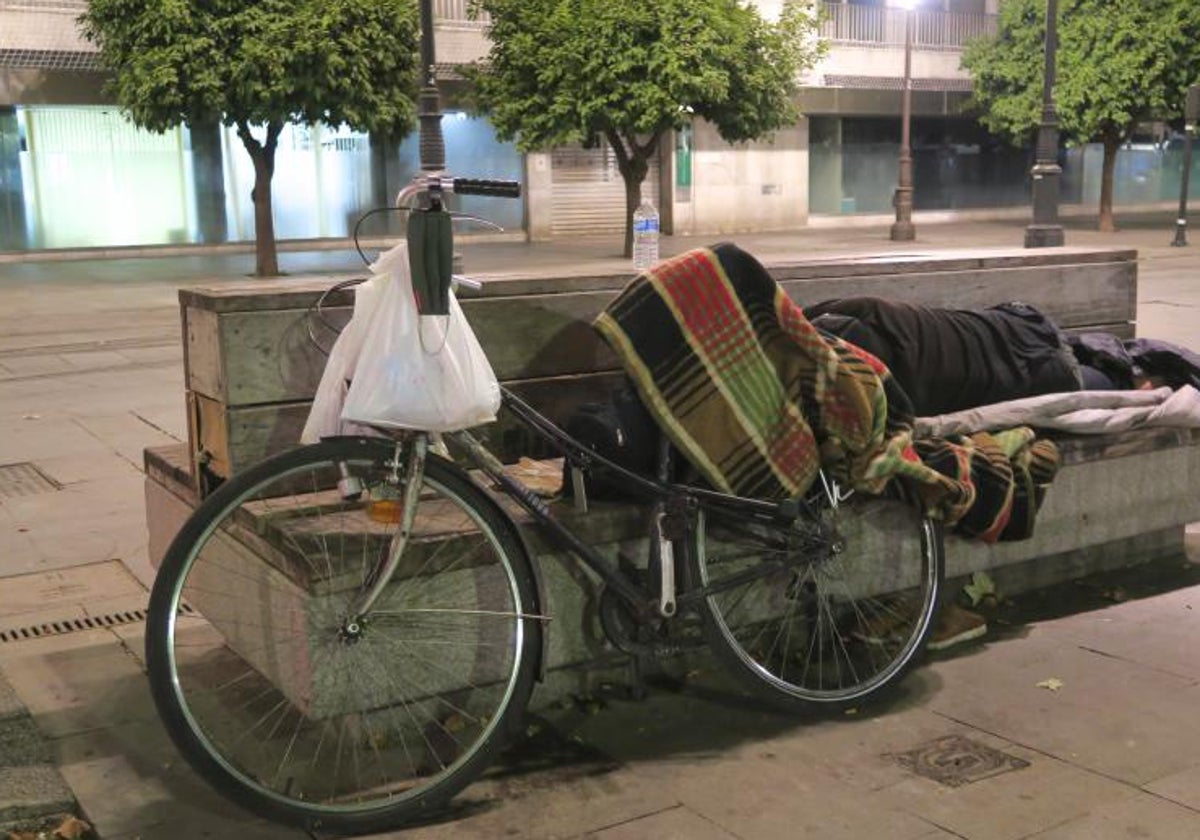 Un hombre duerme en un banco en Sevilla