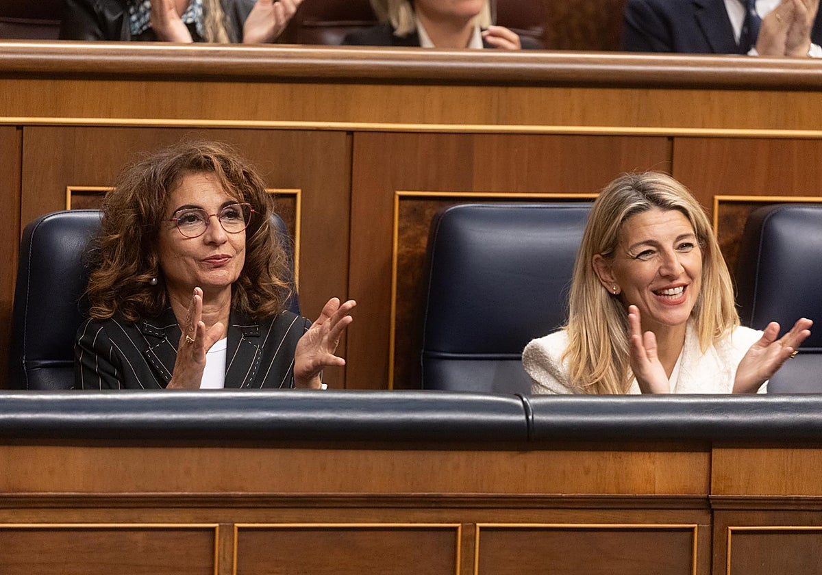 La vicepresidenta primera y ministra de Hacienda, María Jesús Montero (i) y la ministra de Trabajo, Yolanda Díaz, aplauden en un pleno del Congreso