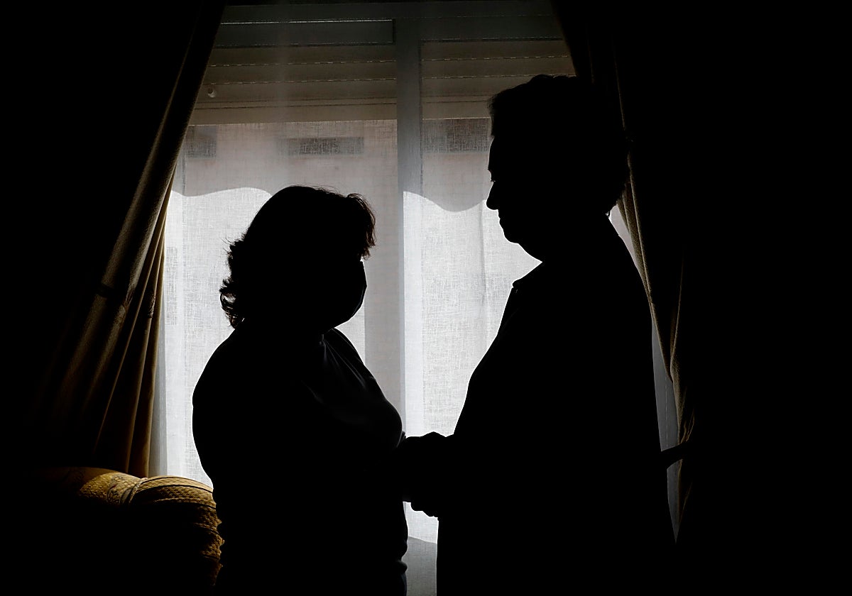 Una mujer junto a la persona a la que cuida en una casa