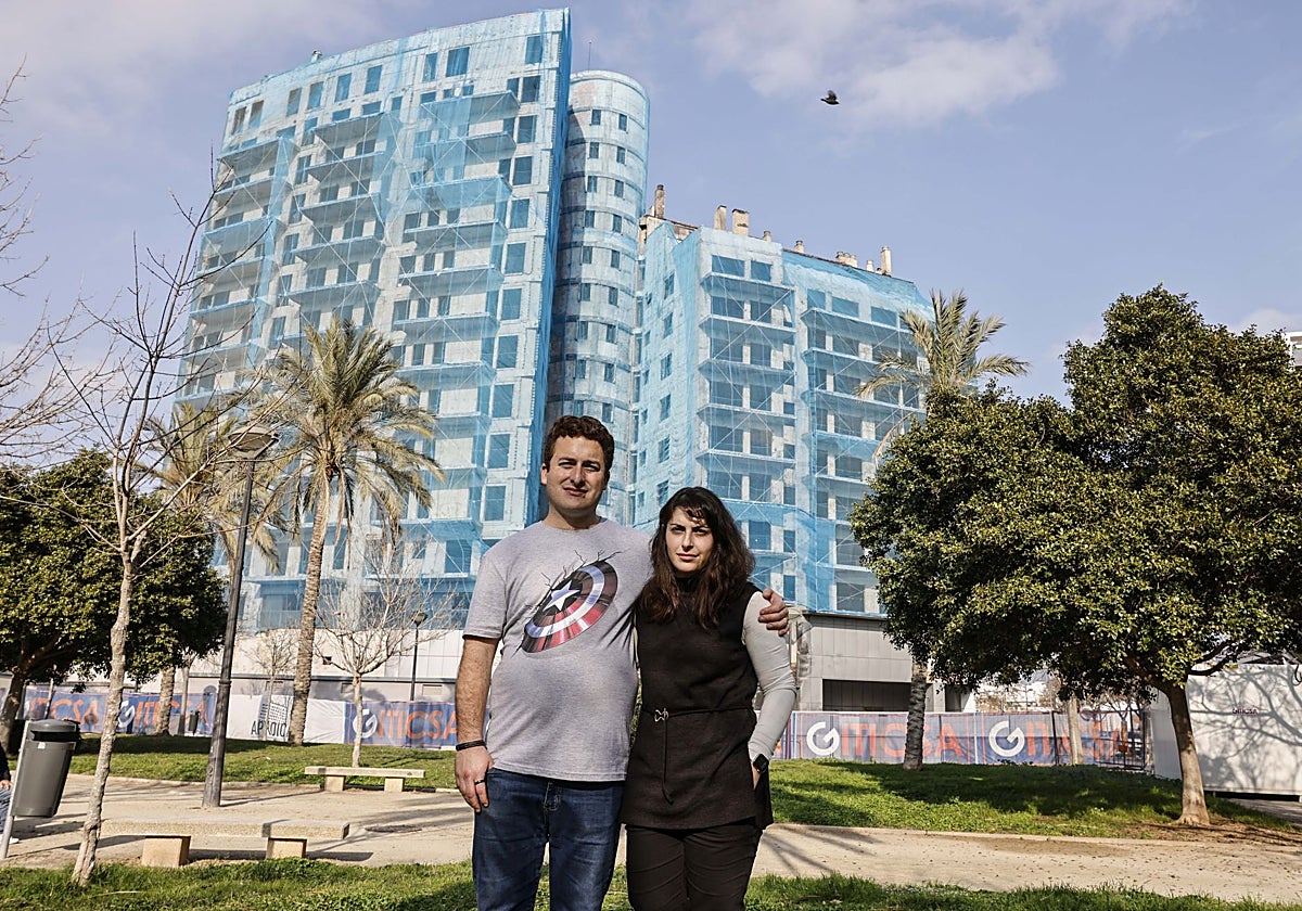 Javier e Inga posan para ABC con el edificio incendiado detrás, en el barrio de Campanar (Valencia)
