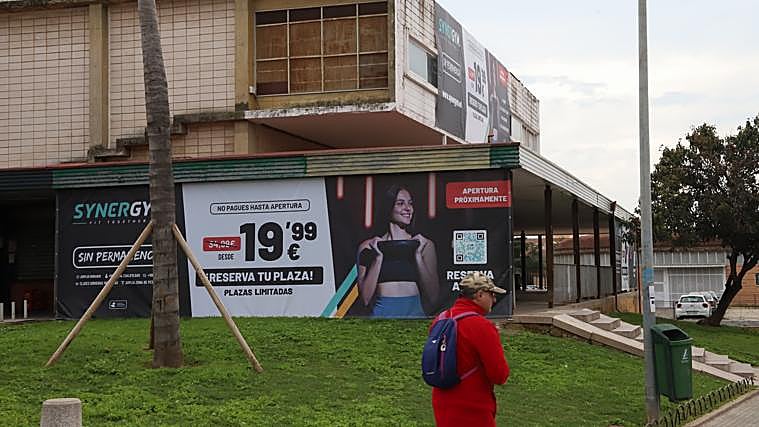 Un hombre pasa delante de las lonas que anuncian un gimnasio en el cine Almirante