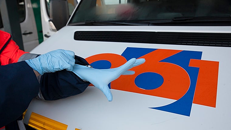 Un profesional se cala los guantes de trabajo junto a un vehículo