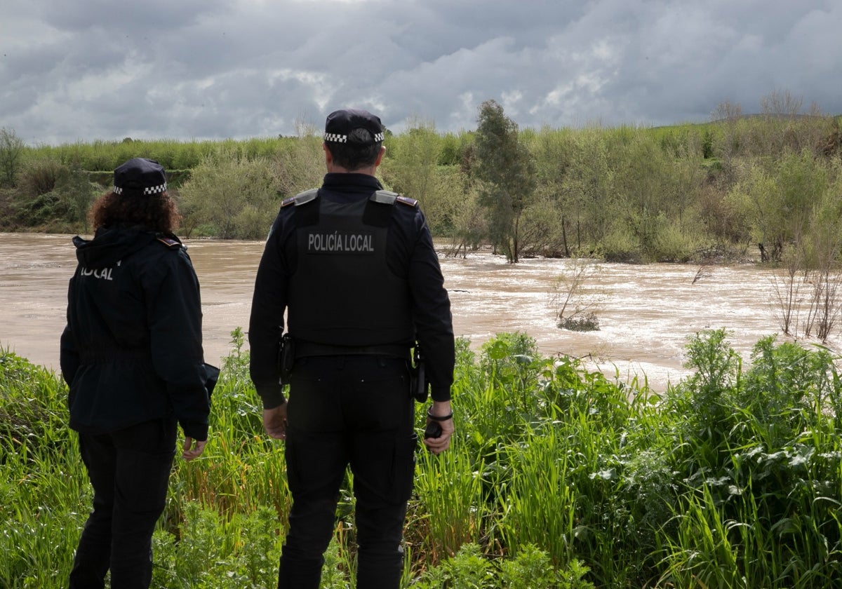 Dos agentes de la Policía Local observan el curso del Guadalquivir