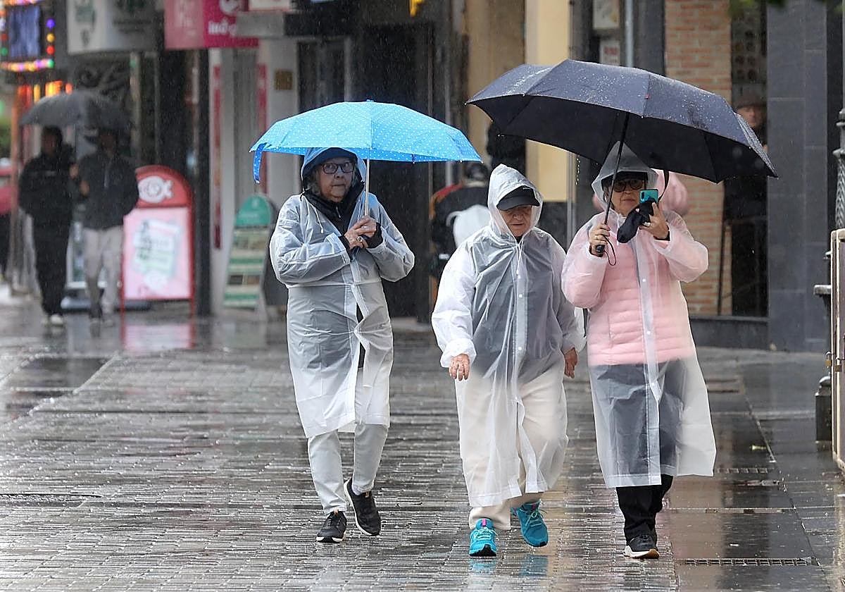Tres turistas pasean por Córdoba bajo la lluvia