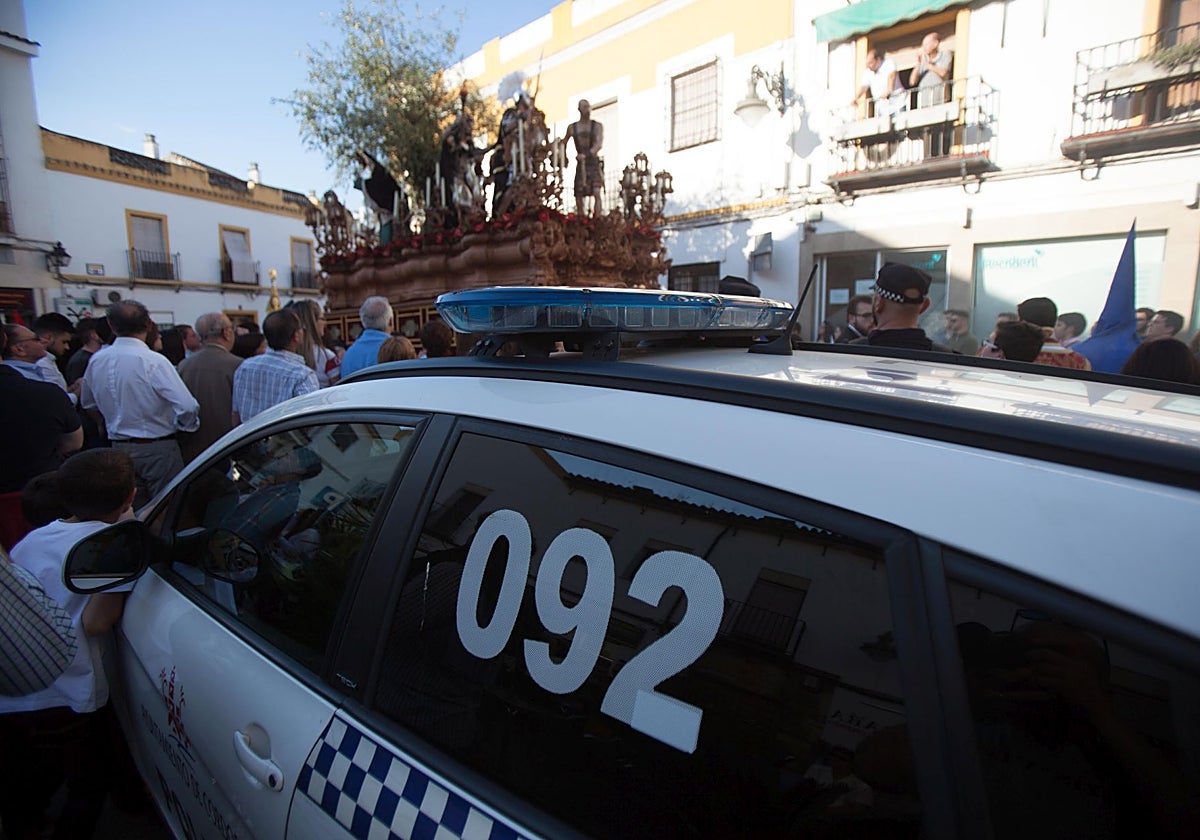 Un coche de la Policía Local de Córdoba y un agente junto al misterio del Prendimiento