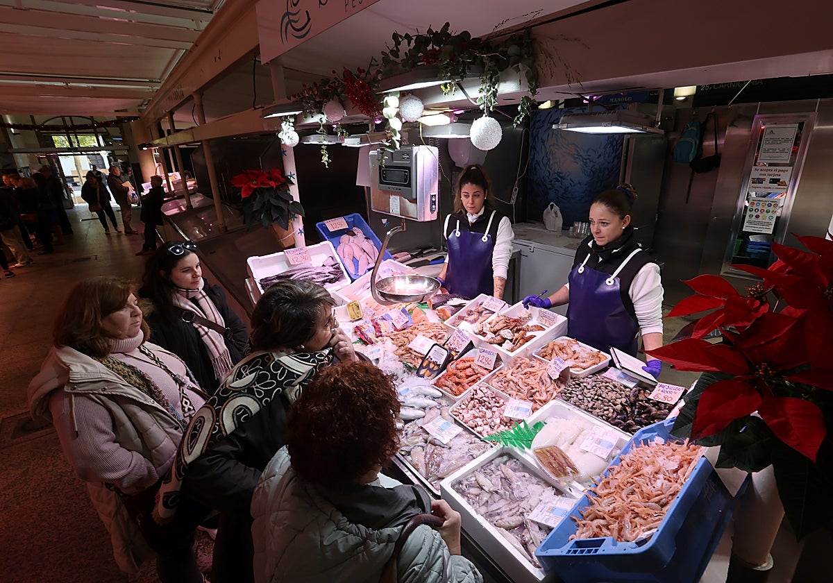 Varias clientas en un puesto de pescado y marisco del mercado de la Corredera