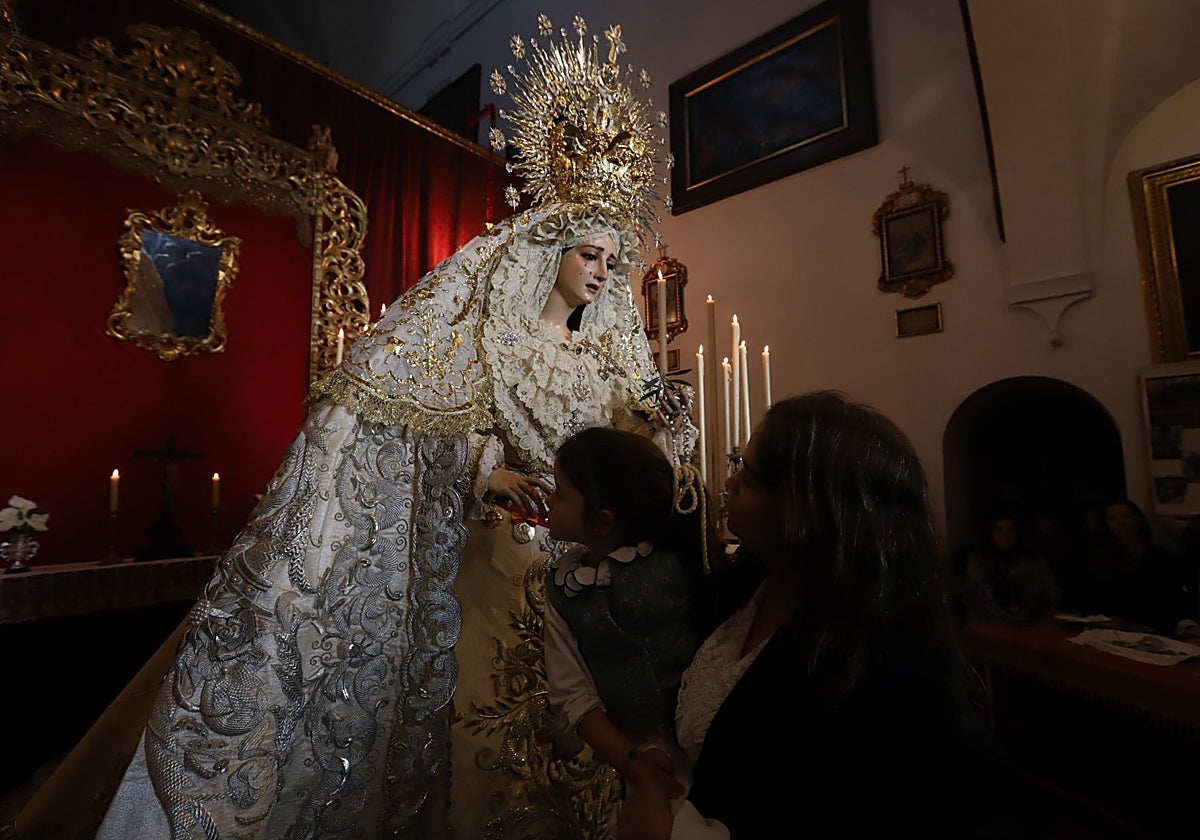 Una niña besa la mano de la Virgen de la Paz y Esperanza