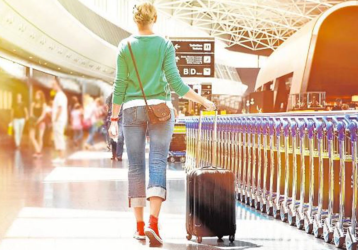 Una joven carga con su maleta a punto de tomar un vuelo en un aeropuerto español