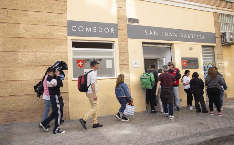 Imagen principal - Los asistentes esperan en fila para recibir el número de su turno para comer; Tino, quien organiza el acceso al Comedor Social San Juan Bautista, con la pequeña Anyelis y sus dos hermanos; y otro de los usuarios, ya sentado a la mesa
