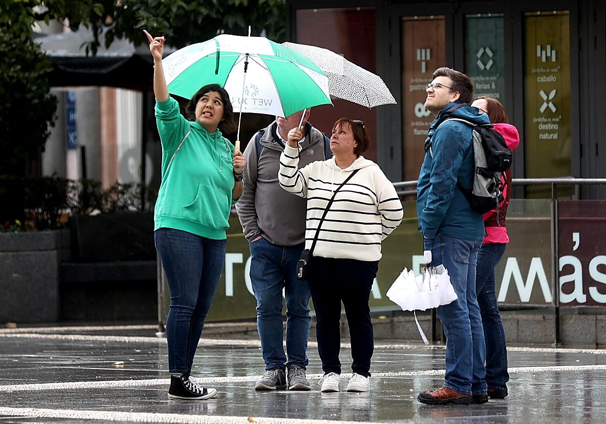 Una guía en marzo enseñando, bajo la lluvia, la ciuad de Córdoba a un grupo de turistas