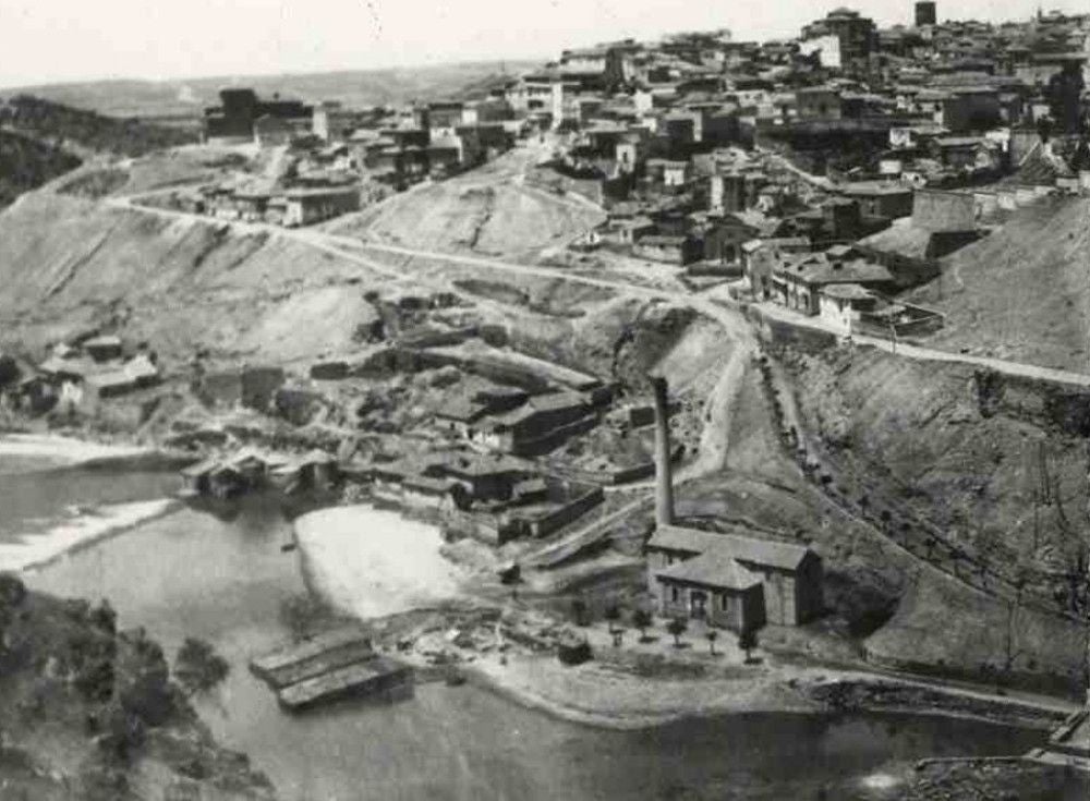 Panorámica de Toledo hacia 1912. Abajo, la central de vapor de la 'Electricista' en la Incurnia. En la orilla, dos barracones para los baños cubiertos autorizados por el Ayuntamiento (Archivo Municipal de Toledo)