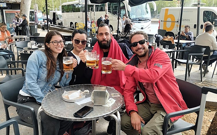 Imagen principal - Arriba, Manuela, Hannah, Elvis y Enrique brindan con cerveza tras su regreso a Madrid. Debajo, viajaros a la espera de noticias en Atocha. A la derecha, las hermanas cordobesas Sandra y Marina 