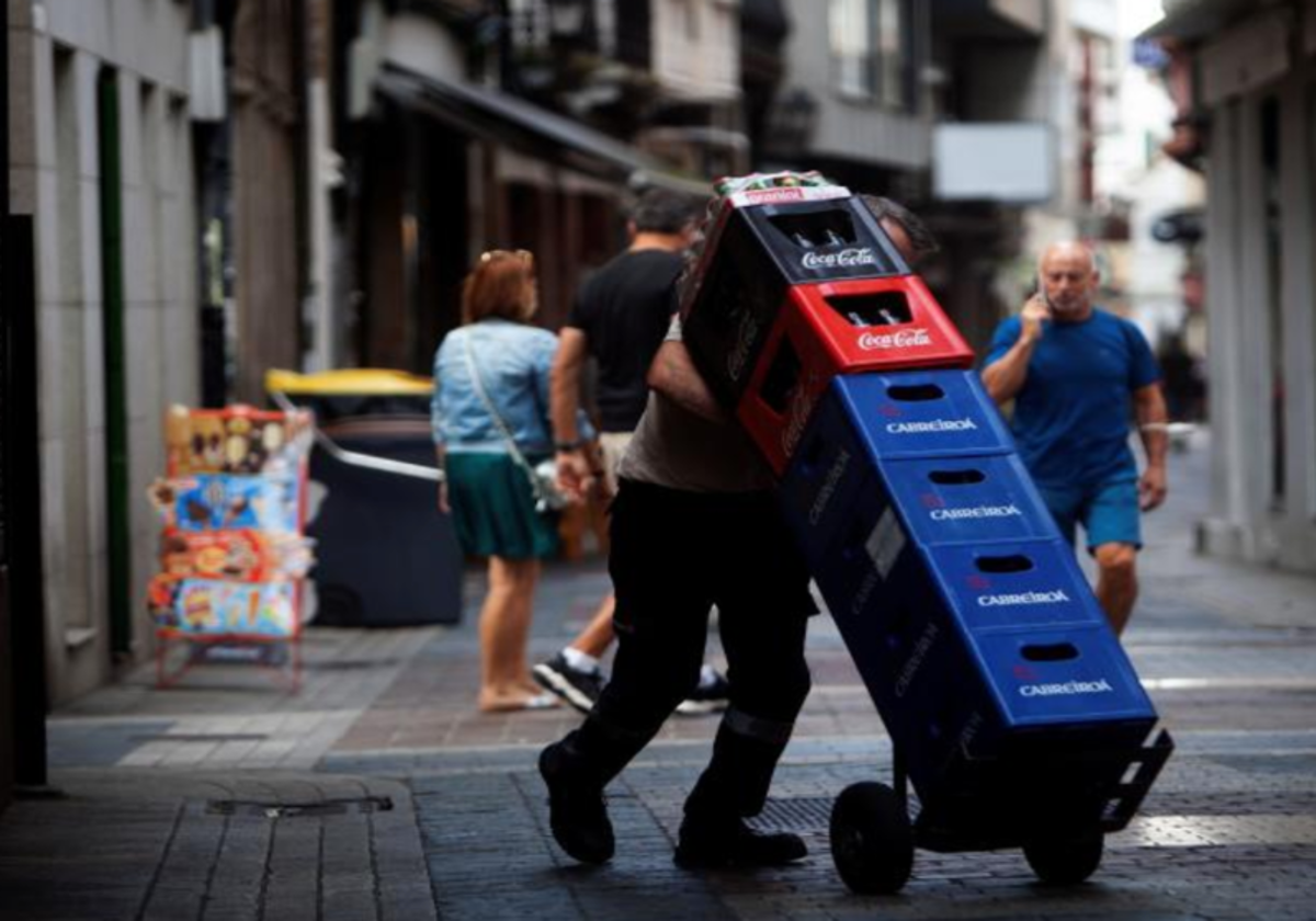 Un repartidor carga con cajas de bebidas en foto de archivo.