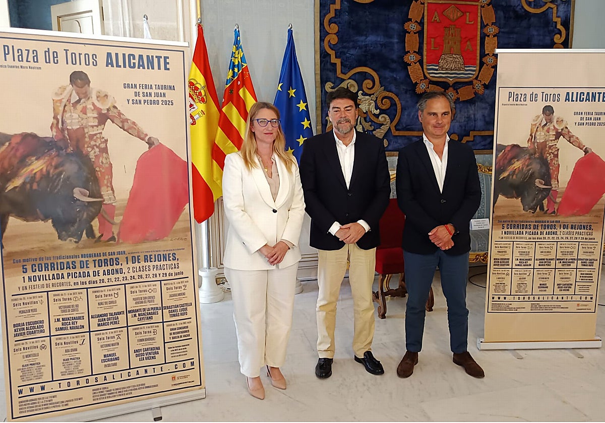 La concejal Mari Carmen de España, el alcalde, Luis Barcala, y el empresario Nacho Lloret, junto al cartel de la Feria de Hogueras 2025