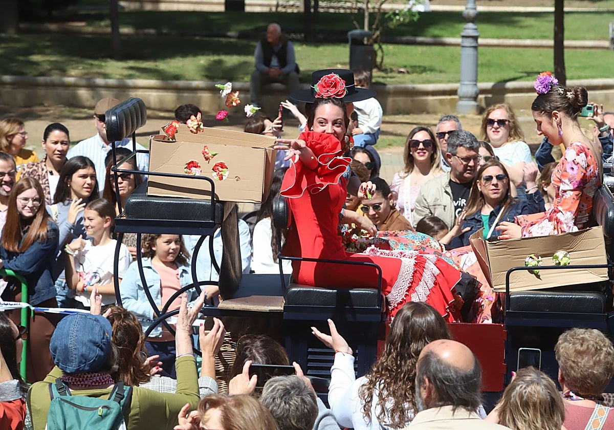 Una joven lanza claveles desde una carroza